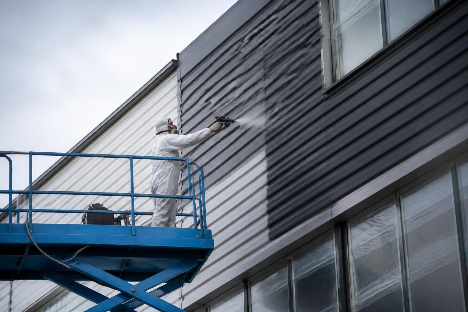 Coatingwerk op metalen gevelbeplating van een bedrijfspand vanaf een hoogwerker